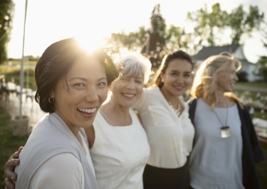 Group of adult female friends smiling and walking through garden