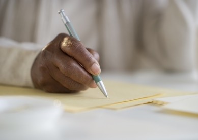 Person writing on paper with pen